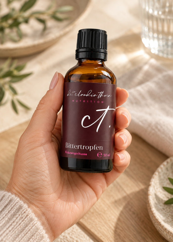 Eine Hand hält die Flasche Bittertropfen.