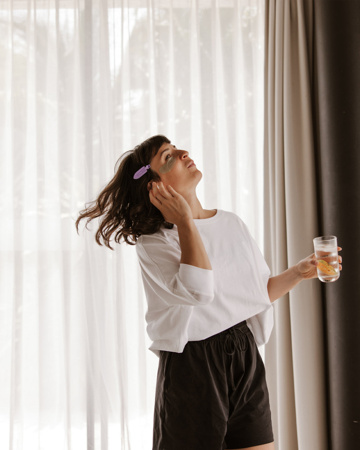 Eine Frau tanzt in einem hellen Raum, ein Glas in der Hand.