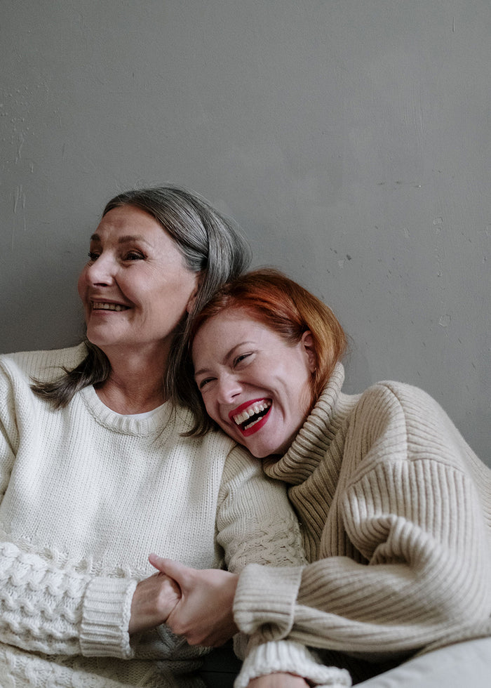 Zwei Frauen lehnen lachend aneinander.